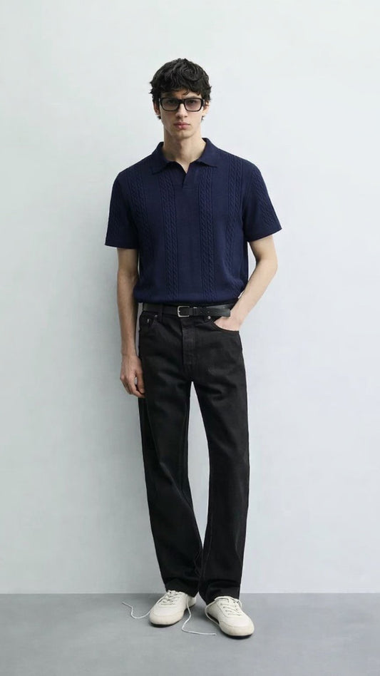 Man wearing a navy polo shirt and black pants against a white background