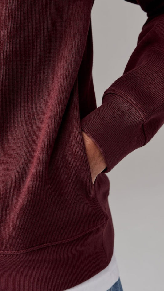 Maroon hoodie worn by a person on a light gray background