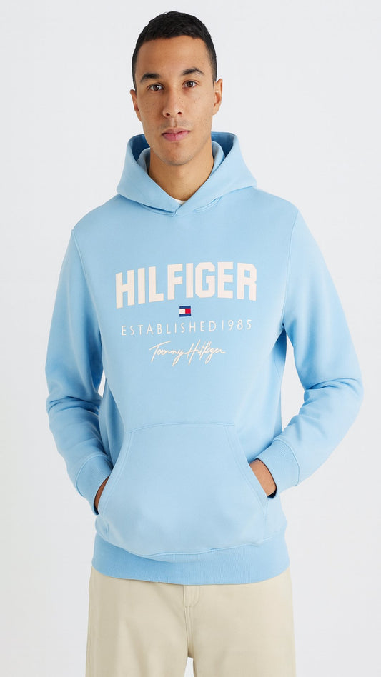 Person wearing a light blue Tommy Hilfiger hoodie on a white background