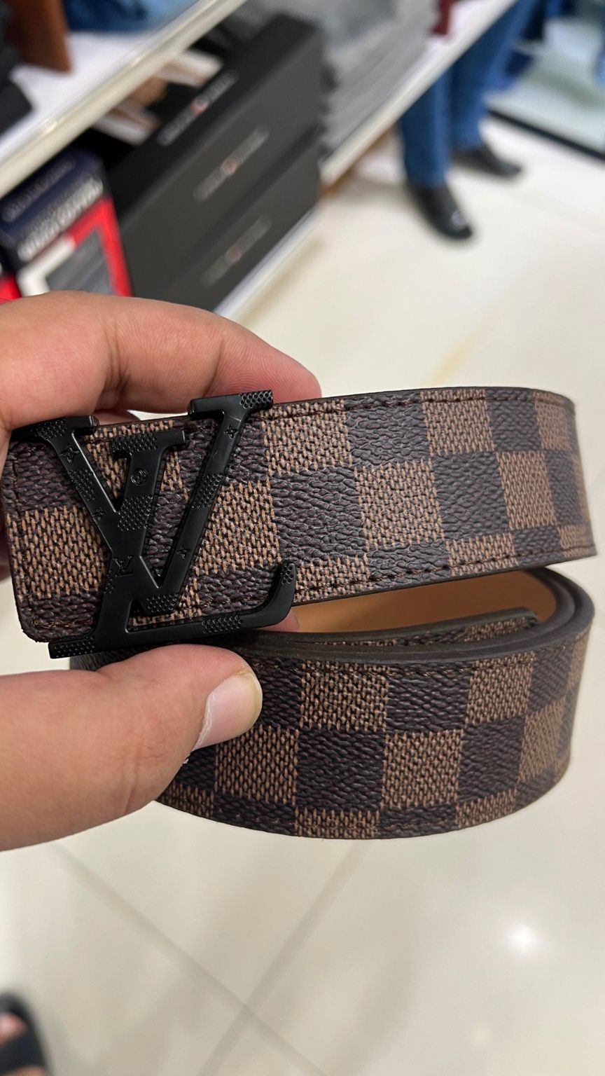 Patterned belt held by a hand on a light background