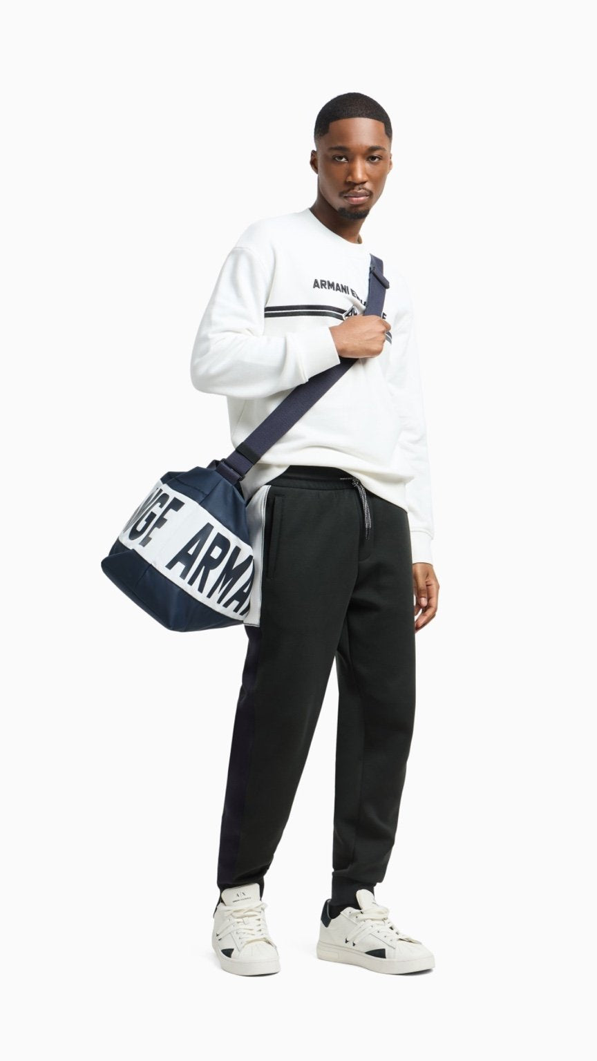 Man holding a navy Armani bag against a white background