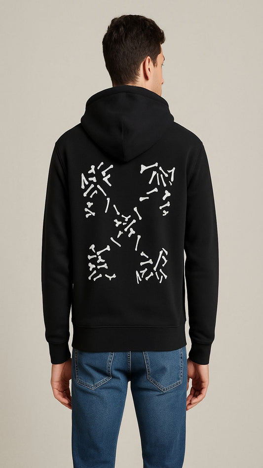 Person wearing a black hoodie with a white geometric design on the back, standing against a beige background.