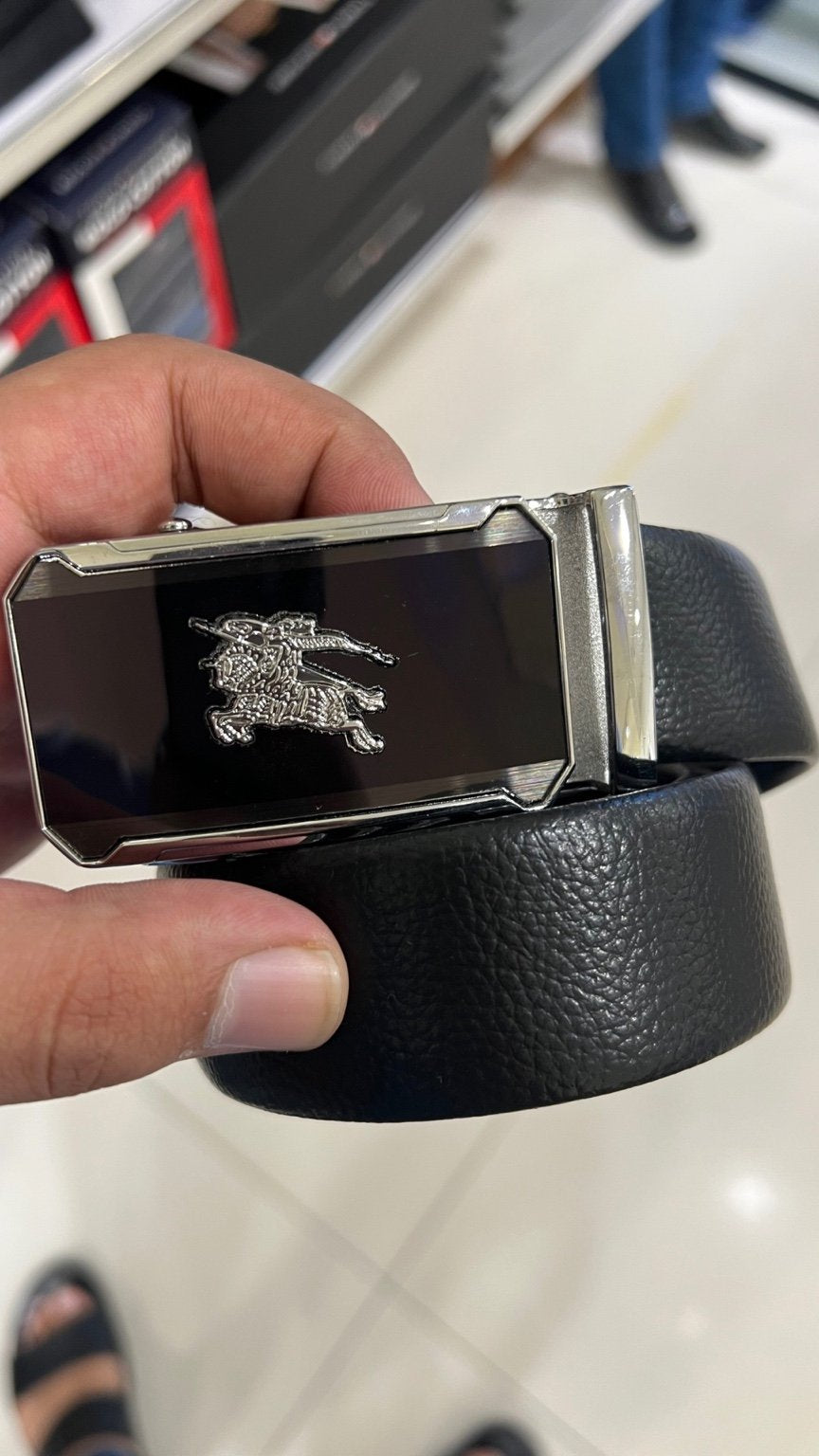 Black belt with a silver buckle held by a hand on a tiled floor background