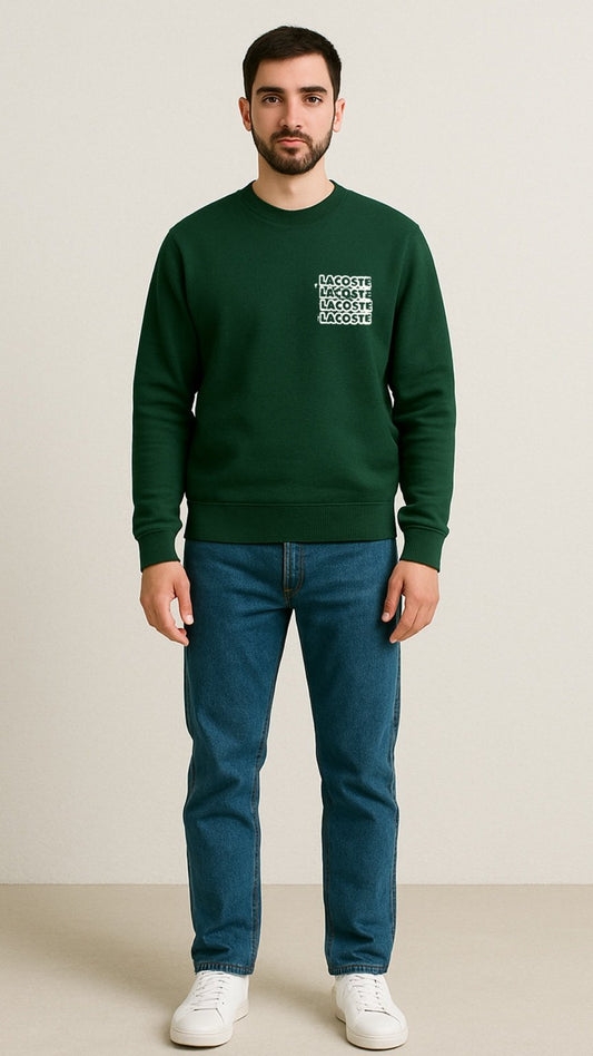 Man wearing a green sweatshirt with text and blue jeans on a beige background