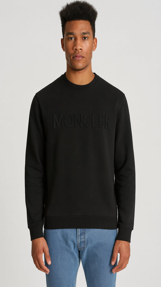 Person wearing a black Moncler sweatshirt on a light gray background