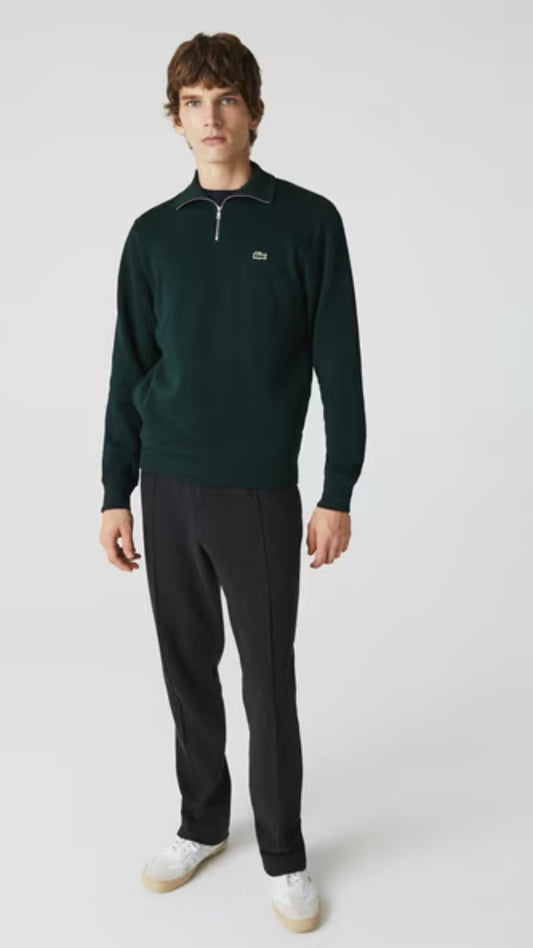 Man wearing a dark green sweater and black pants on a white background