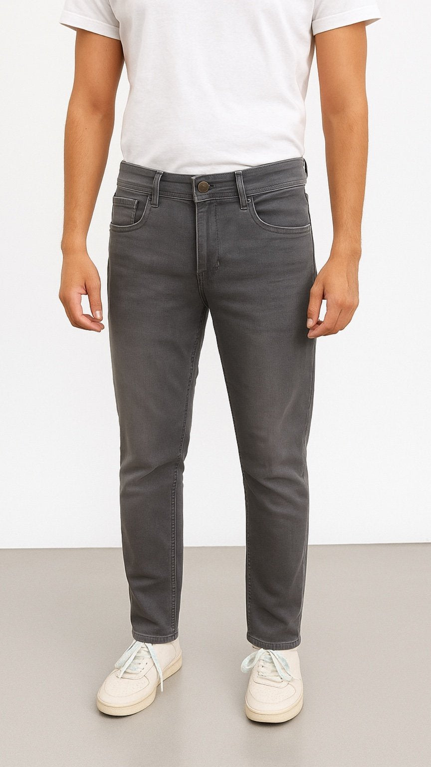 Person wearing gray jeans and a white t-shirt on a plain background