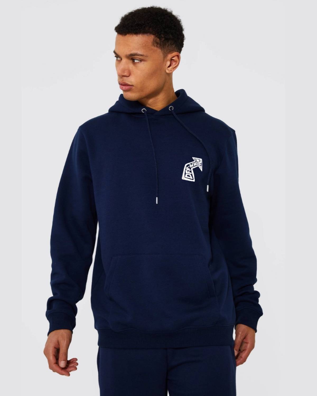 Person wearing a navy hoodie with a logo on a plain background