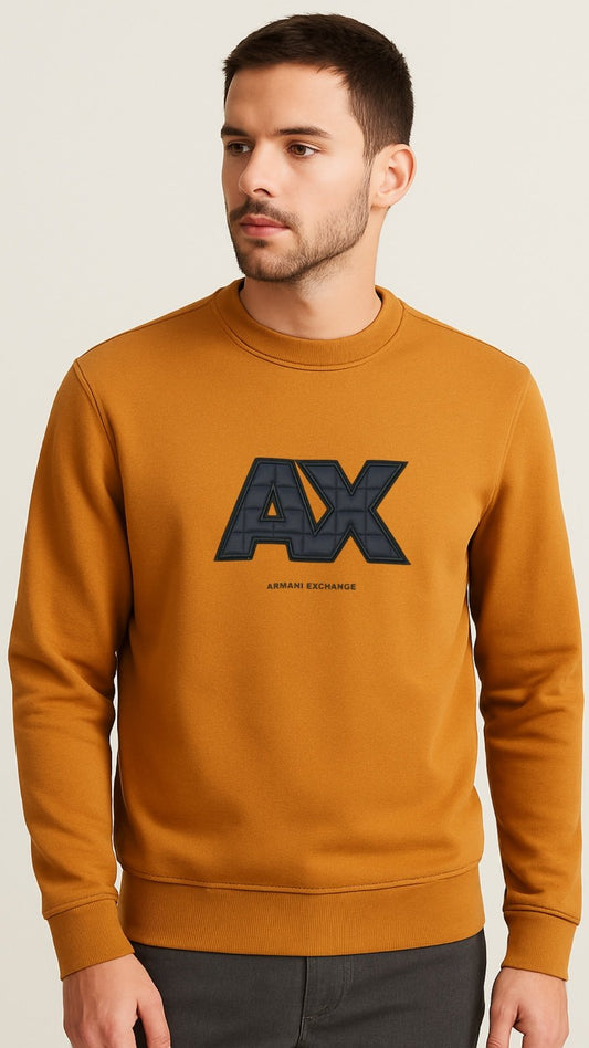 Man wearing a mustard yellow sweatshirt with A|X logo on a beige background