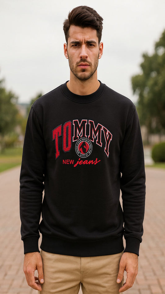 Man wearing a black Tommy Hilfiger sweatshirt outdoors.
