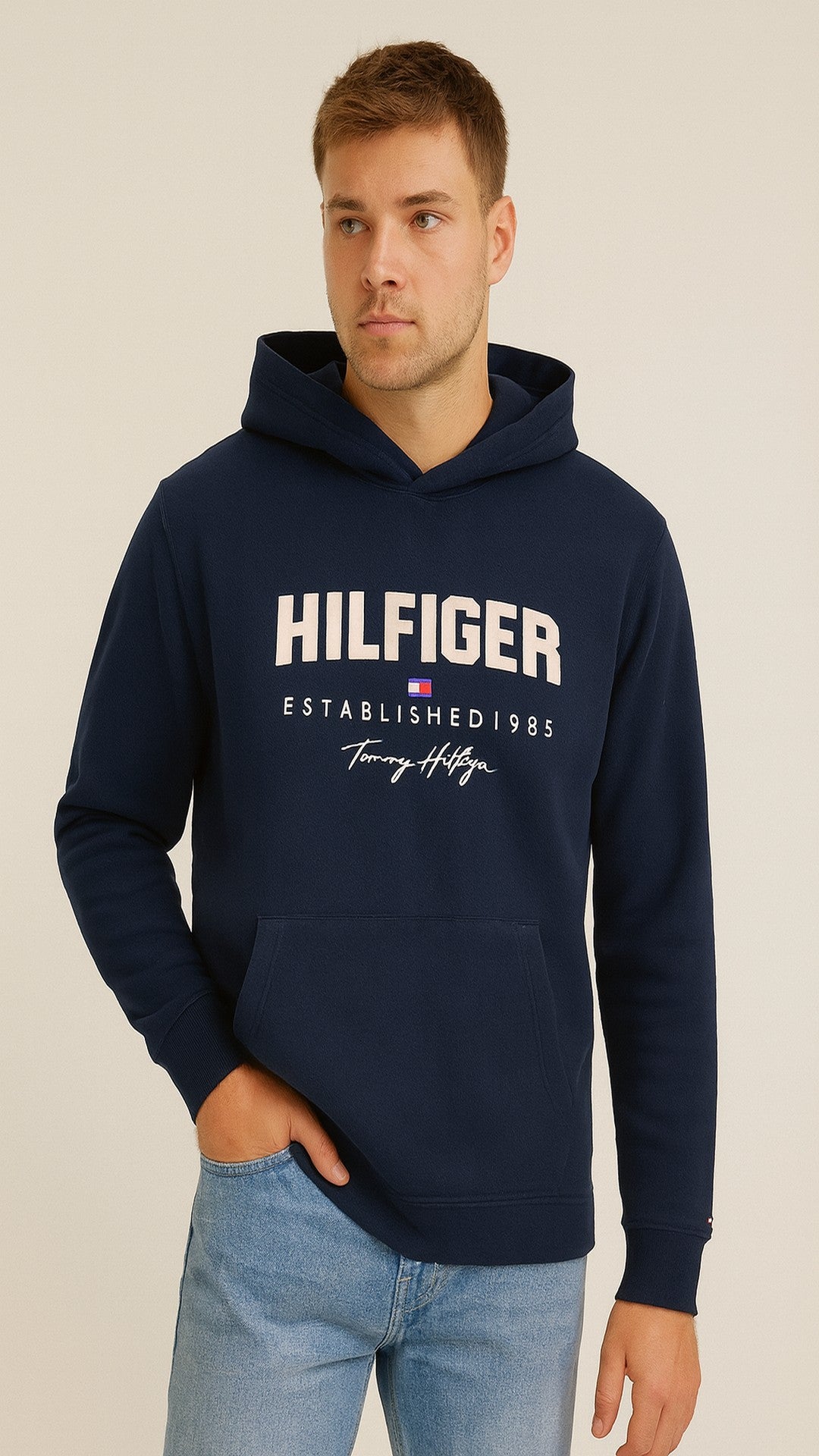 Man wearing a navy Tommy Hilfiger hoodie on a beige background