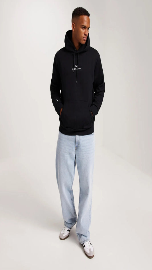 Man wearing a black hoodie and light blue jeans on a white background