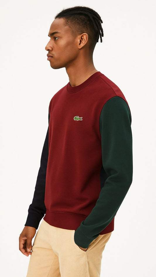 Man wearing a red and green color-blocked sweatshirt with a visible brand logo on a beige background
