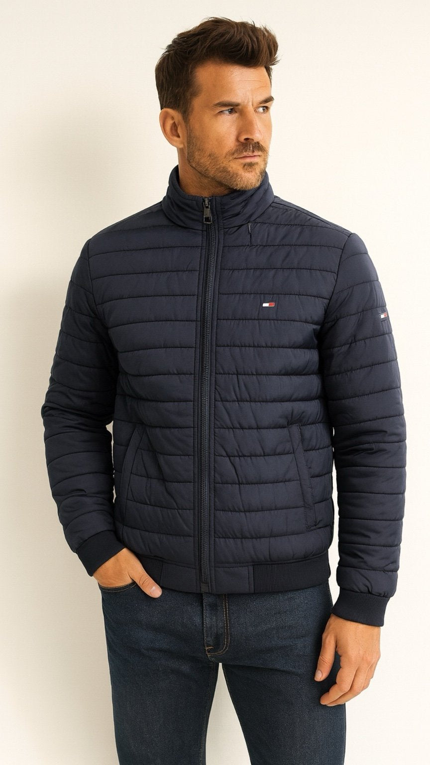 Man wearing a navy blue quilted jacket against a white background