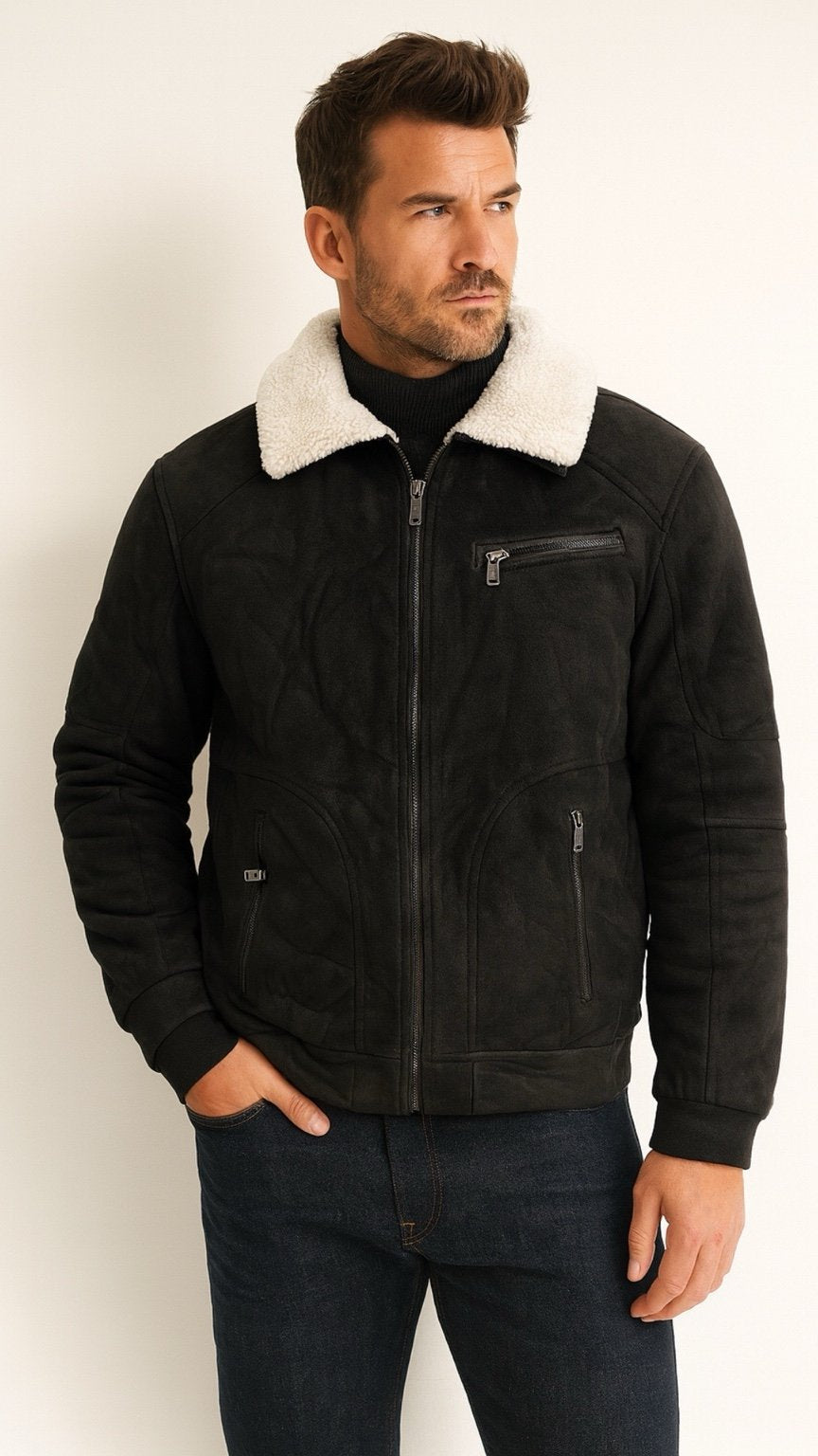 Man wearing a black jacket with a white fur collar against a plain background