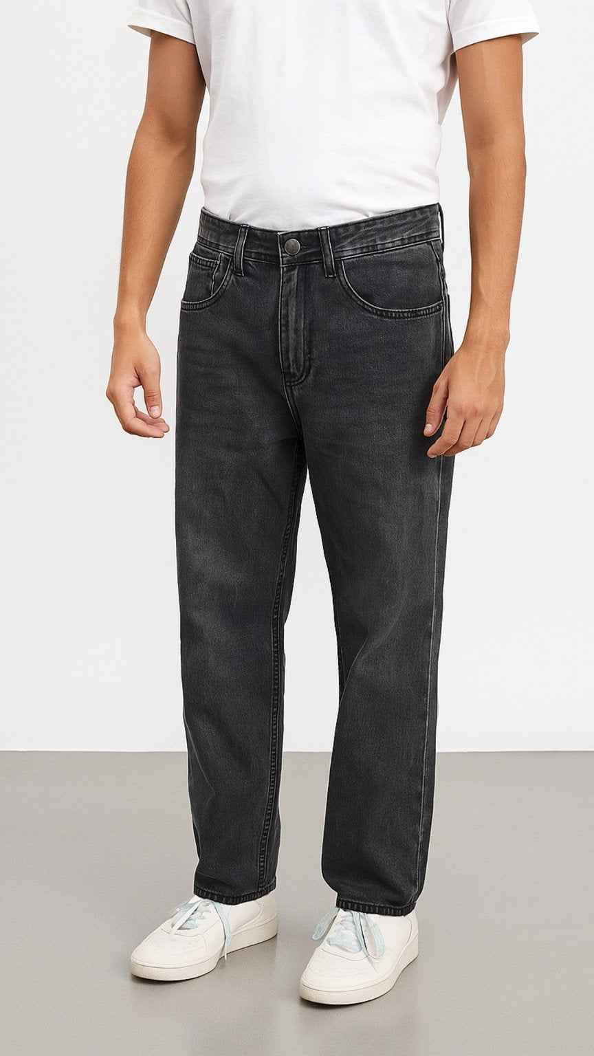 Person wearing black jeans and white sneakers on a plain background