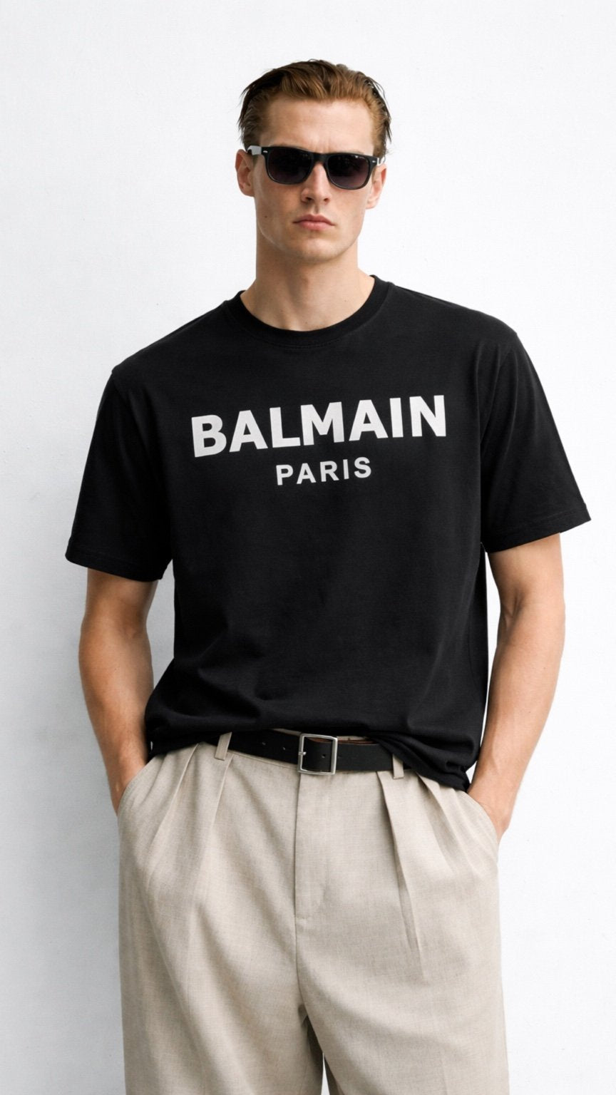 Man wearing a black Balmain t-shirt and sunglasses on a white background