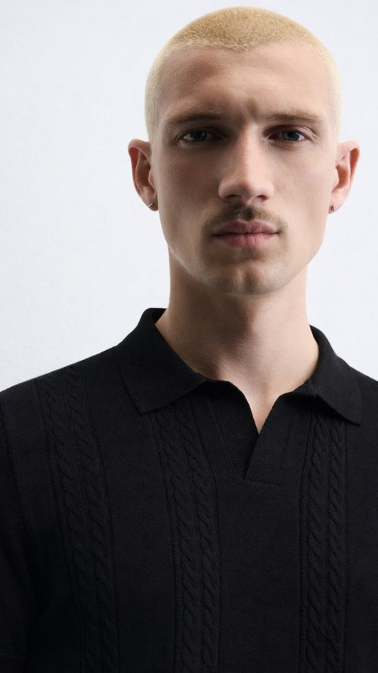 Man wearing a black cable knit sweater against a white background