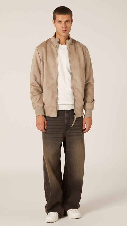 Man wearing a beige jacket, white shirt, and dark pants on a plain background