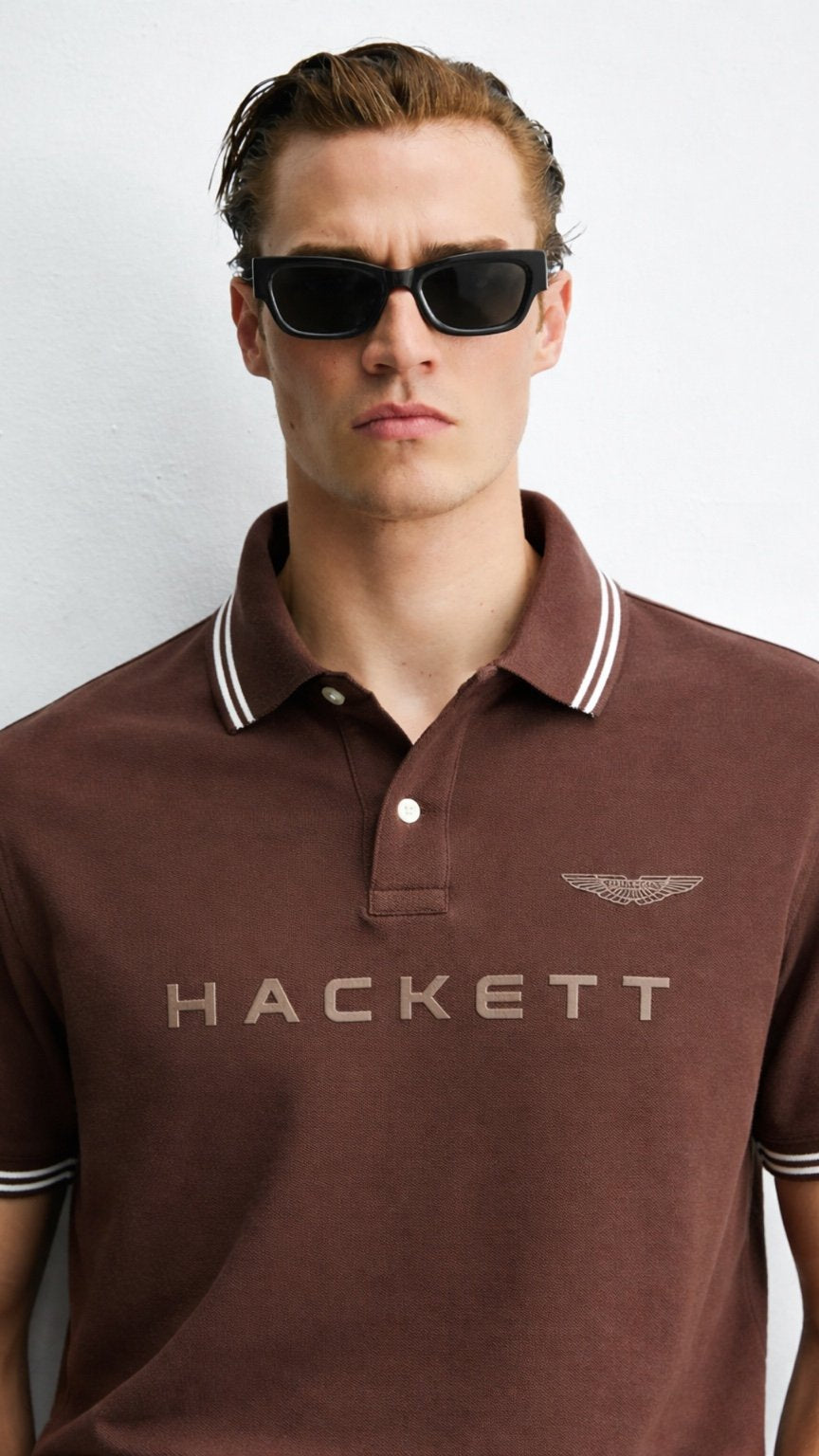 Man wearing a brown Hackett polo shirt with sunglasses on a white background