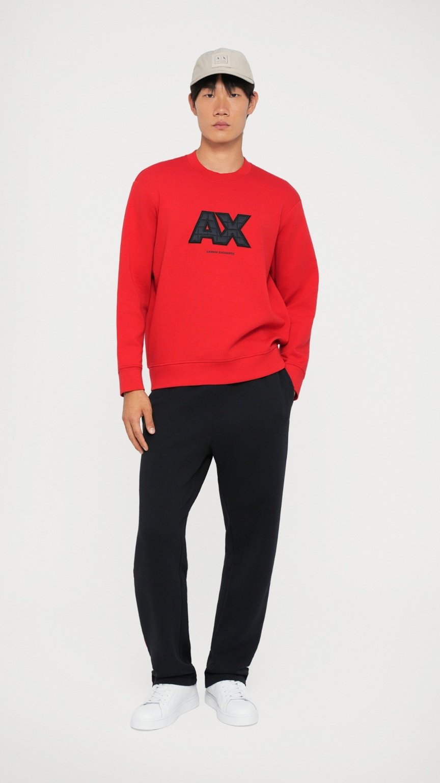 Person wearing a red sweatshirt with a logo, black pants, and white shoes on a white background