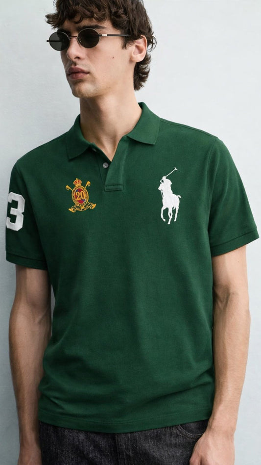 Man wearing a green polo shirt with logos on a plain background