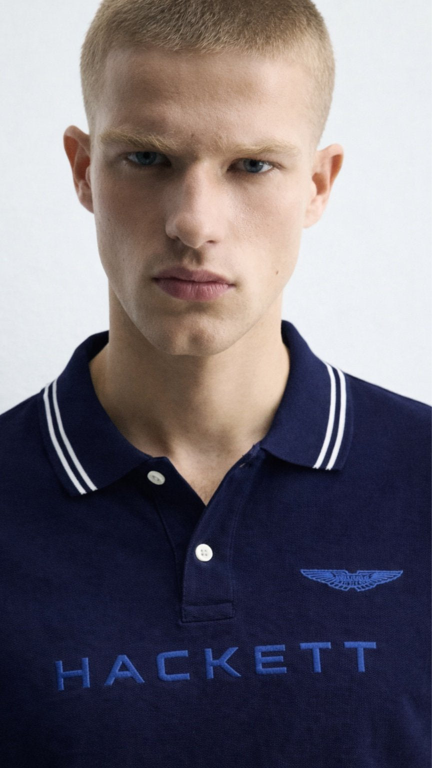 Man wearing a navy Hackett polo shirt against a white background