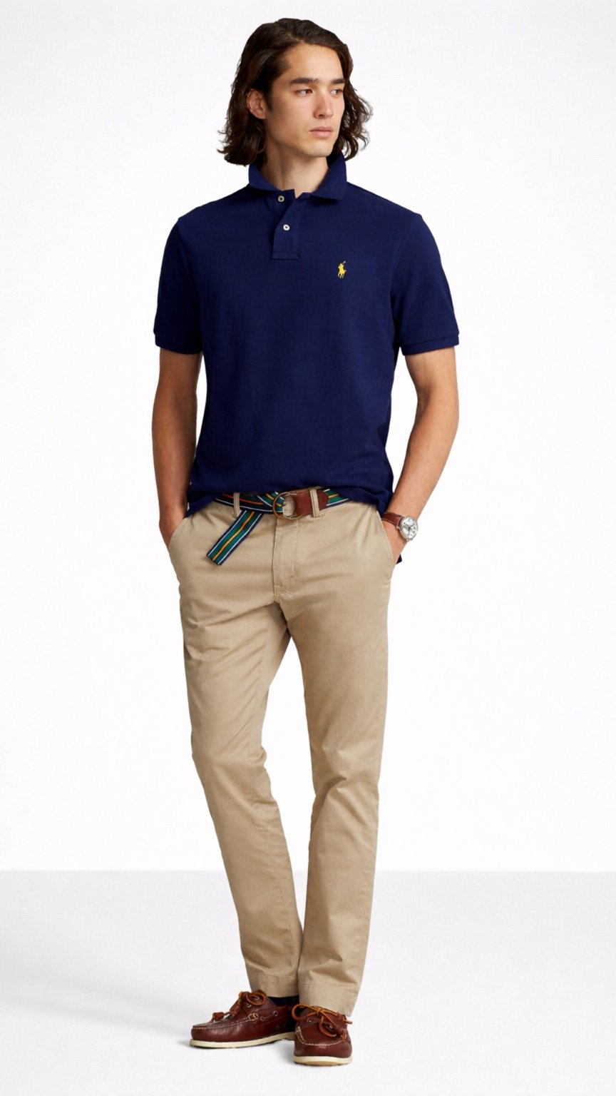 Man wearing a navy blue polo shirt and beige pants on a white background