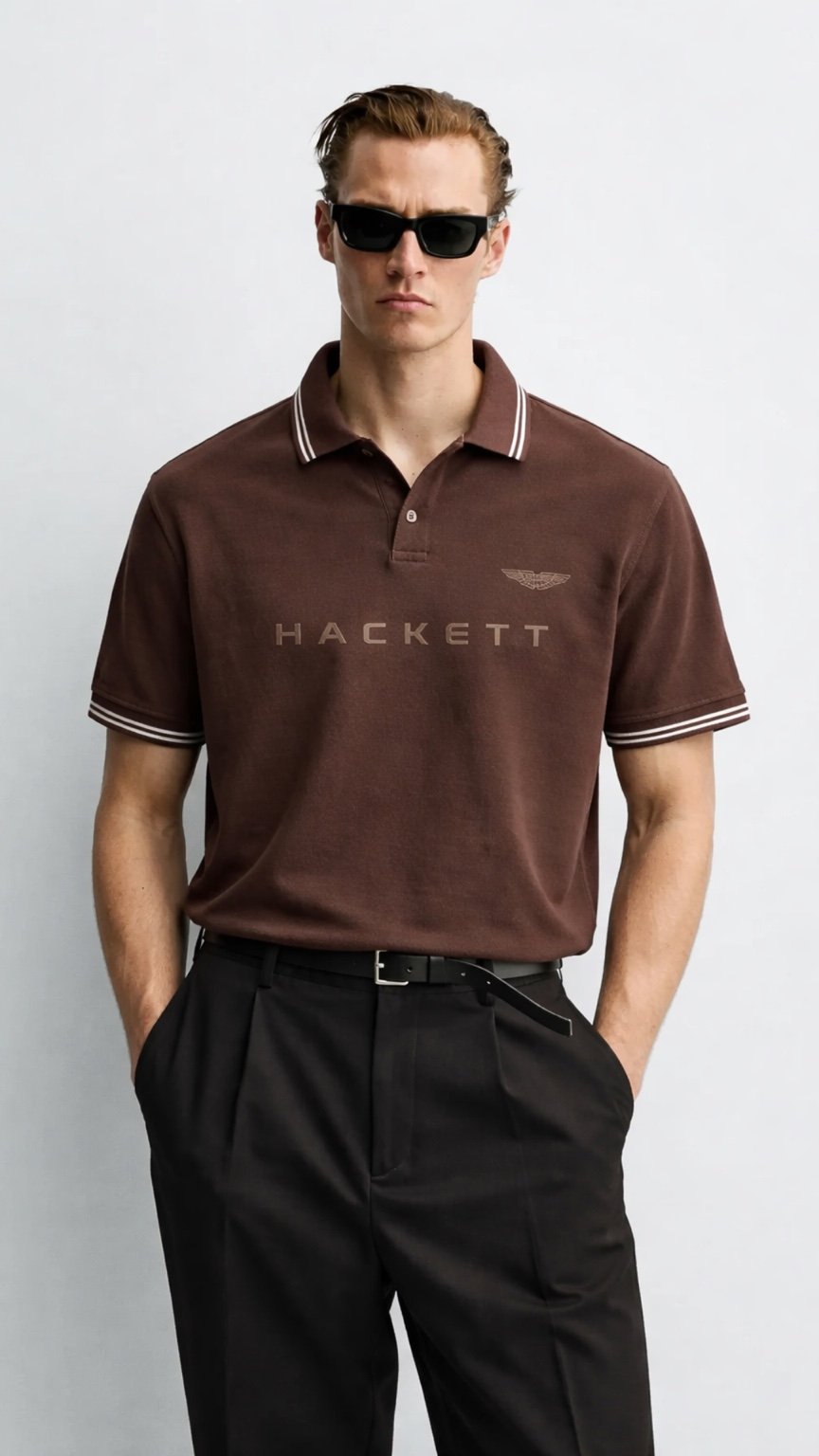 Man wearing a brown Hackett polo shirt and black pants on a white background