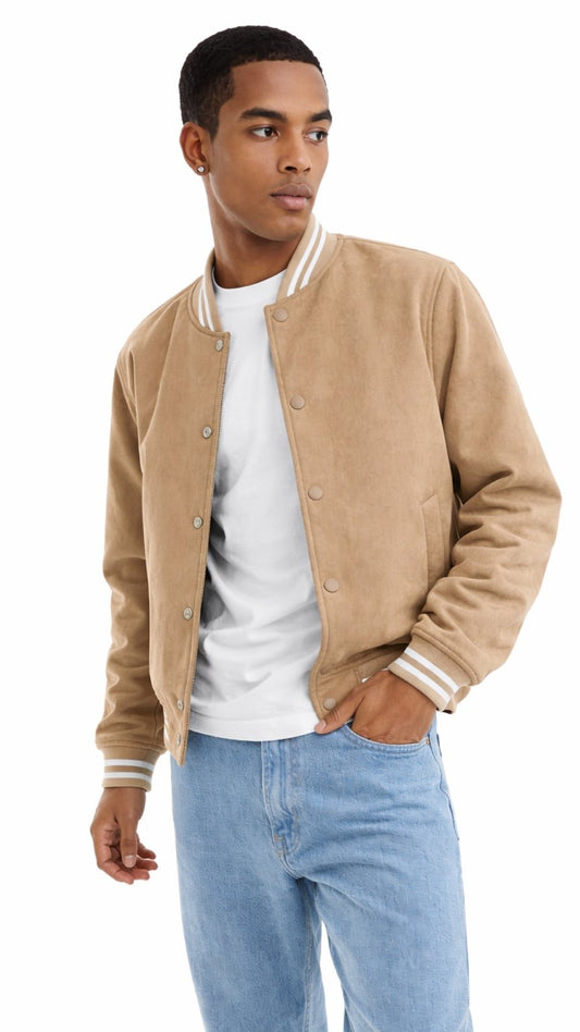 Man wearing a beige varsity jacket over a white shirt and blue jeans on a white background