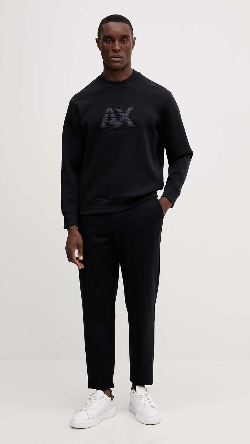 Man wearing a black Armani Exchange sweater and pants on a white background
