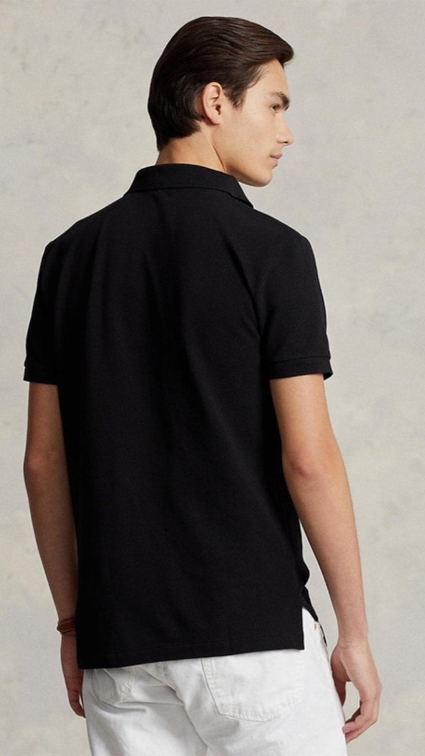 Person wearing a black polo shirt against a neutral background
