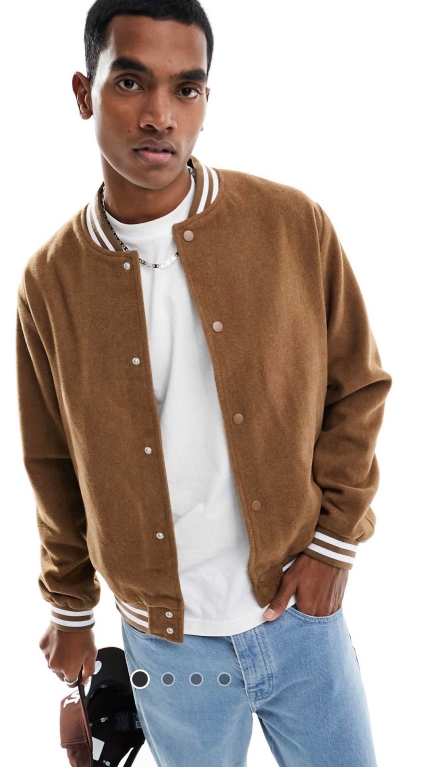 Man wearing a brown varsity jacket over a white shirt and blue jeans on a white background