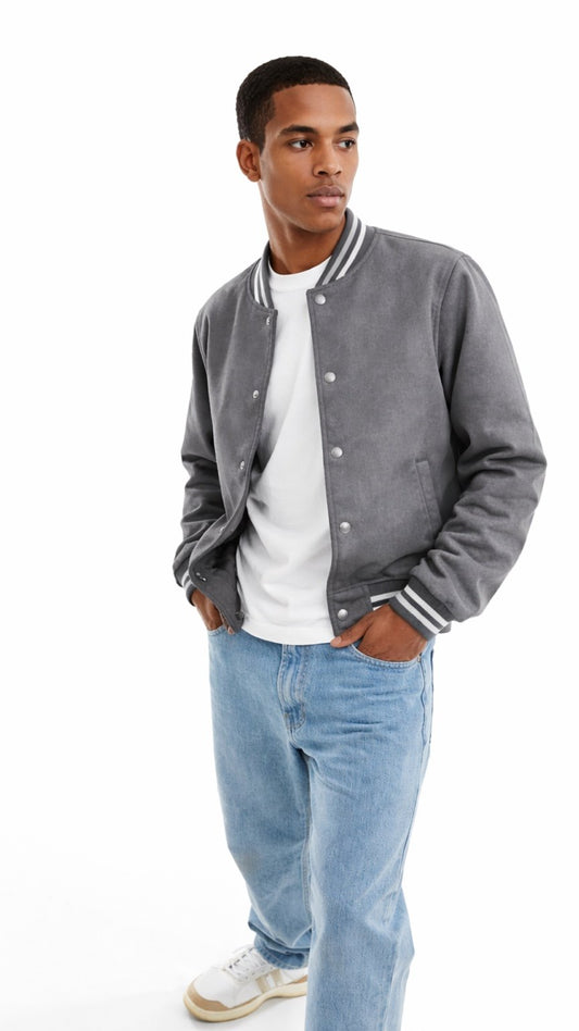 Man wearing a gray varsity jacket, white t-shirt, and blue jeans on a white background