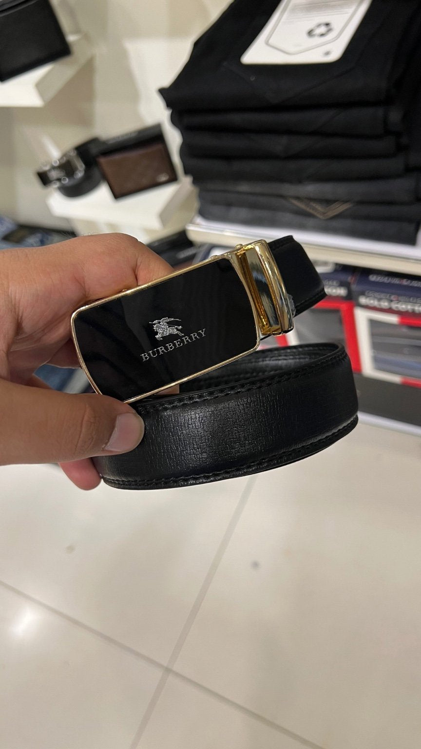 Black belt with gold buckle held by a hand in a store setting