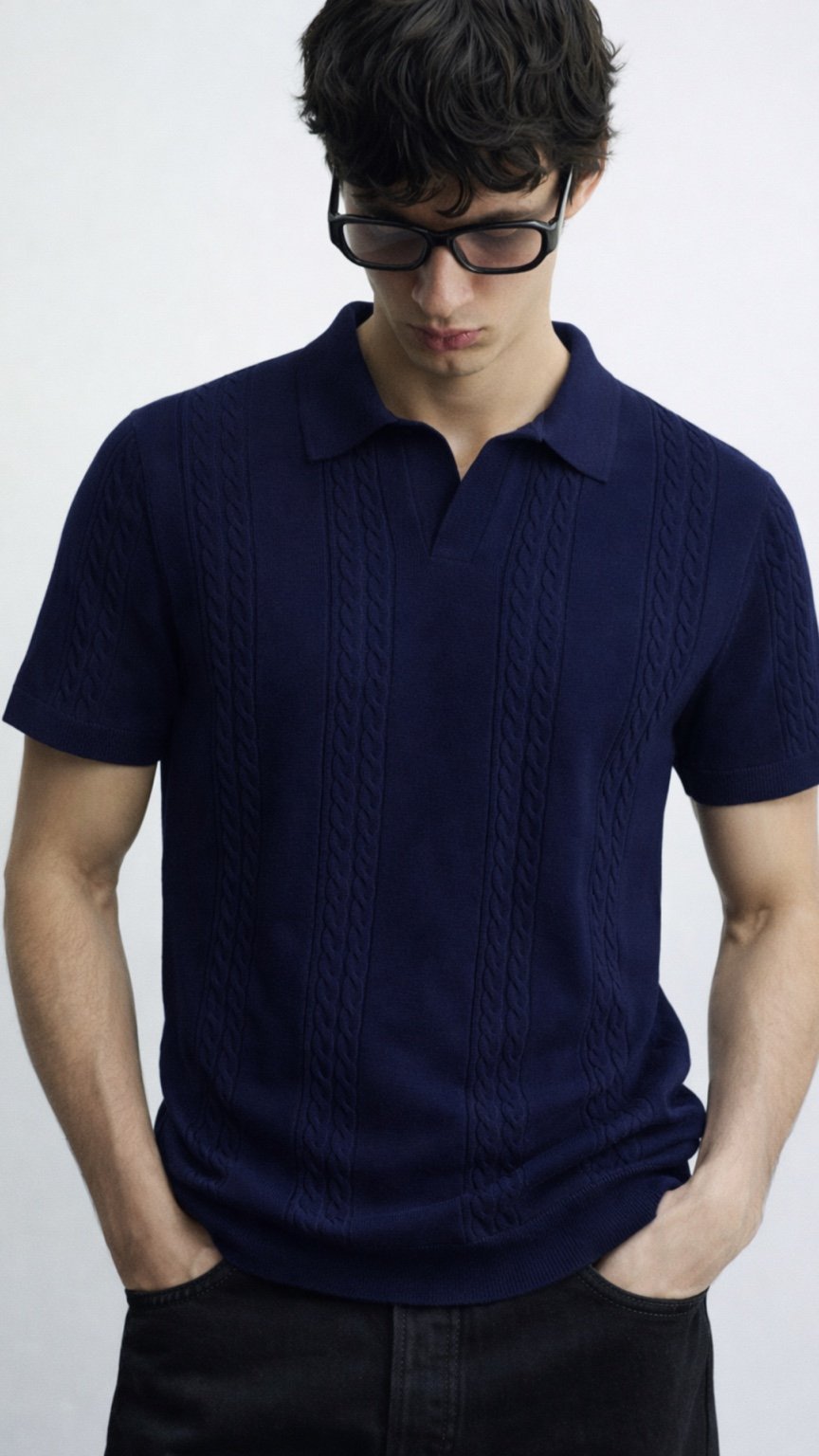 Man wearing a navy blue cable knit polo shirt against a white background