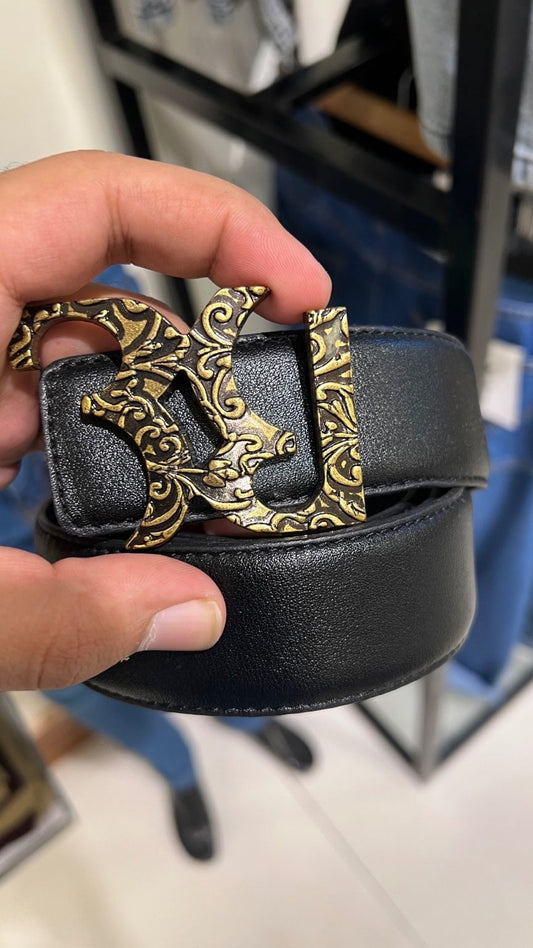 Black belt with gold buckle held by a hand against a blurred background