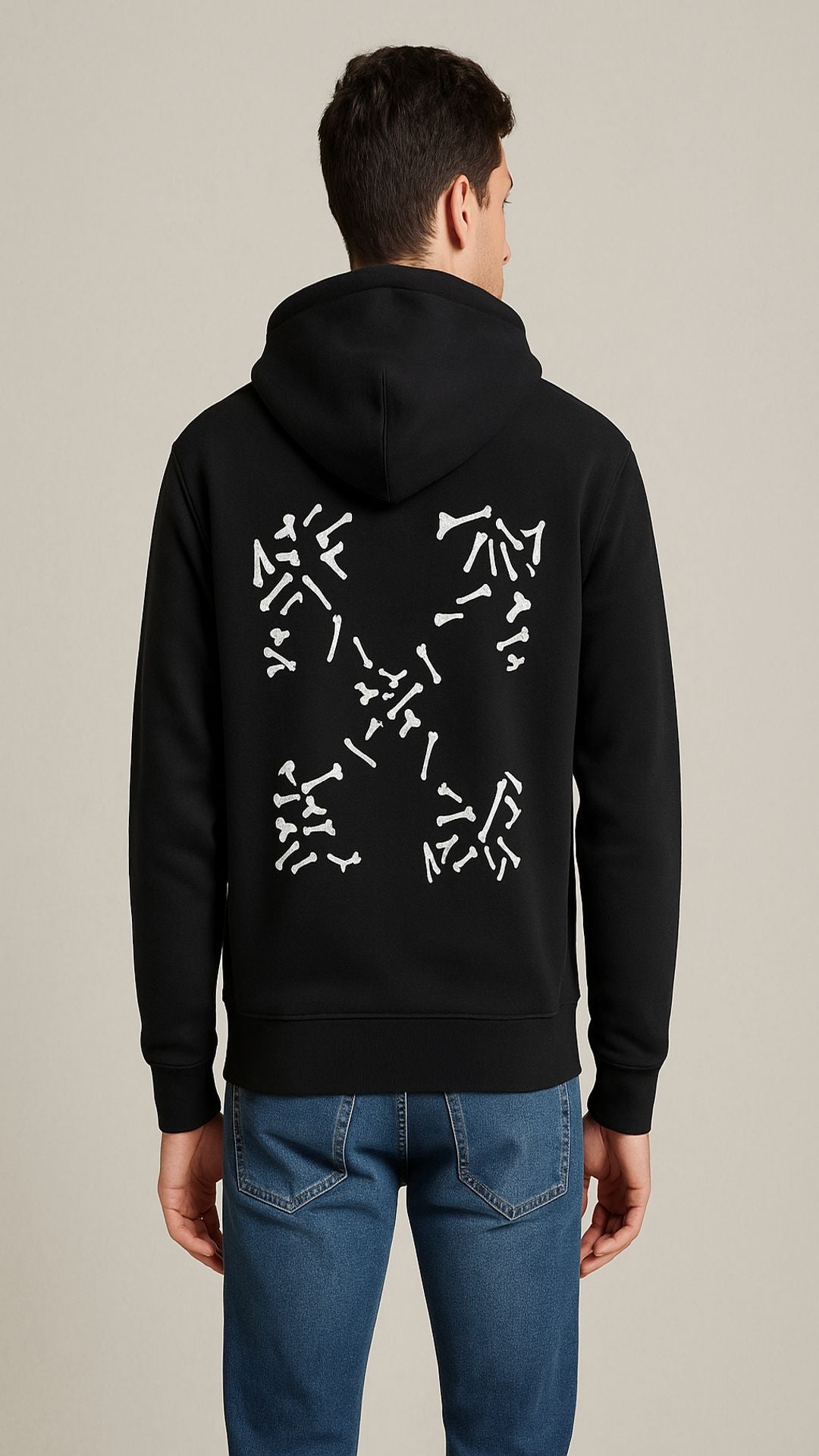 Person wearing a black hoodie with a white geometric design on the back, standing against a beige background.