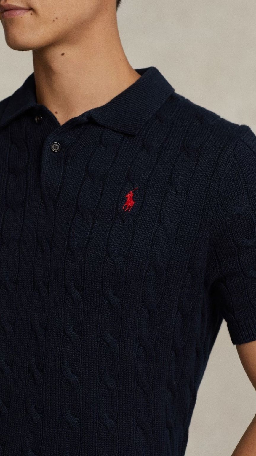 Navy blue cable knit polo shirt with a red logo on a neutral background