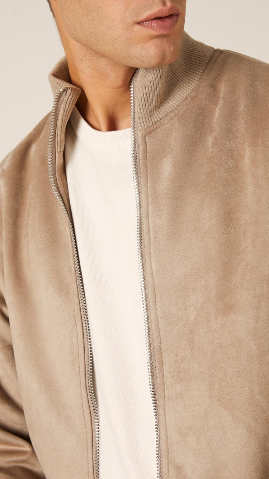 Close-up of a beige suede jacket with a white shirt underneath on a light background