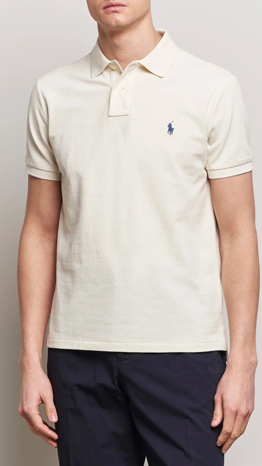 Man wearing a cream-colored polo shirt with a small logo on a plain background