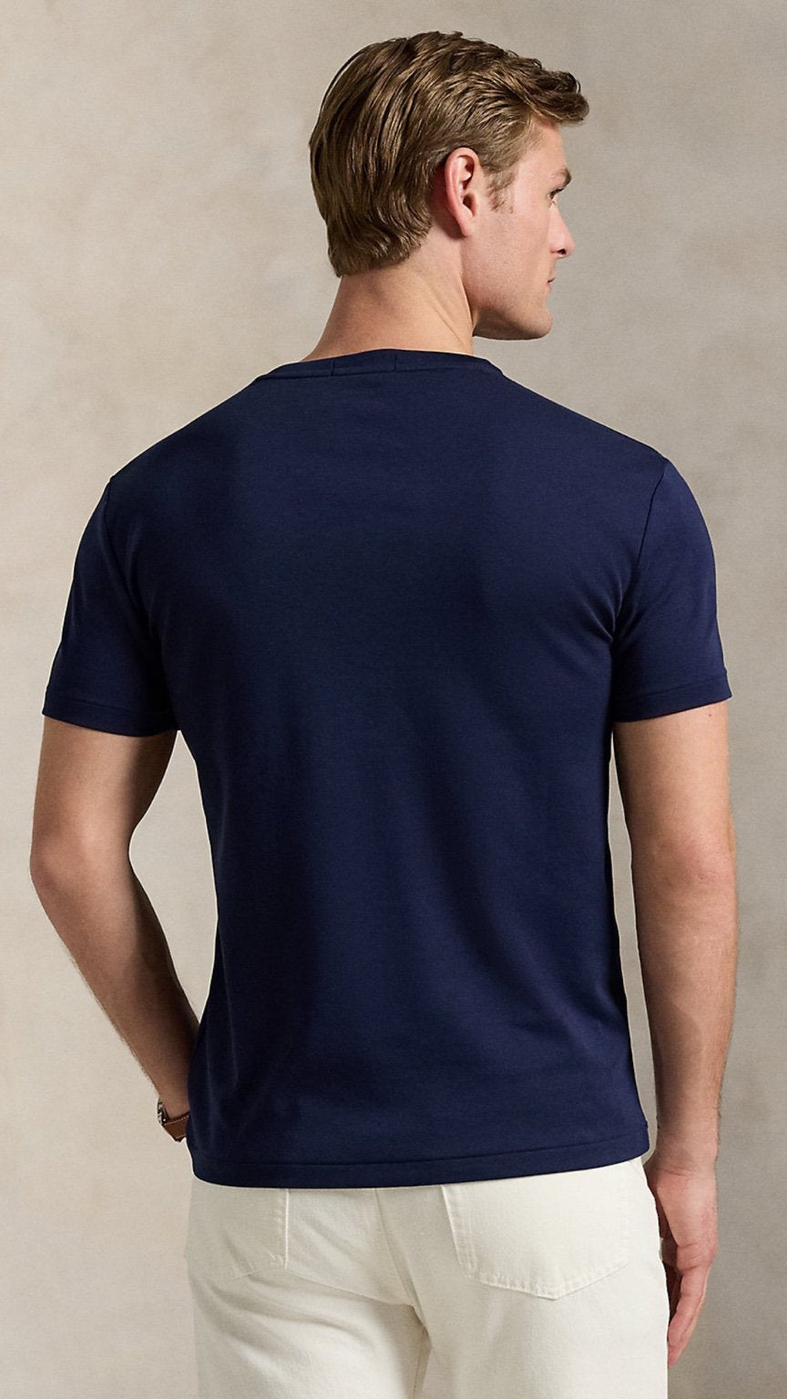 Man wearing a navy blue t-shirt against a beige background