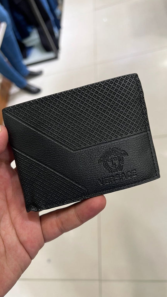 Black Versace wallet held in a hand with a blurred background