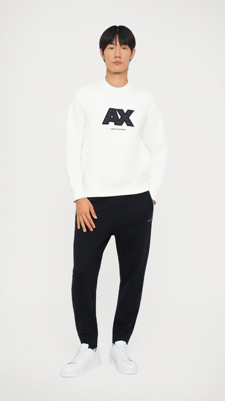 Person wearing a white sweatshirt with a logo and black pants on a white background