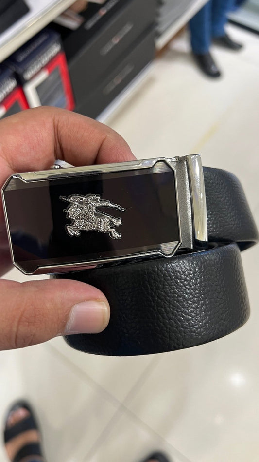 Black belt with a silver buckle held by a hand on a tiled floor background