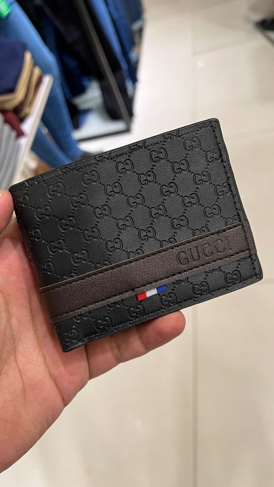Black Gucci wallet held in a hand with a blurred background