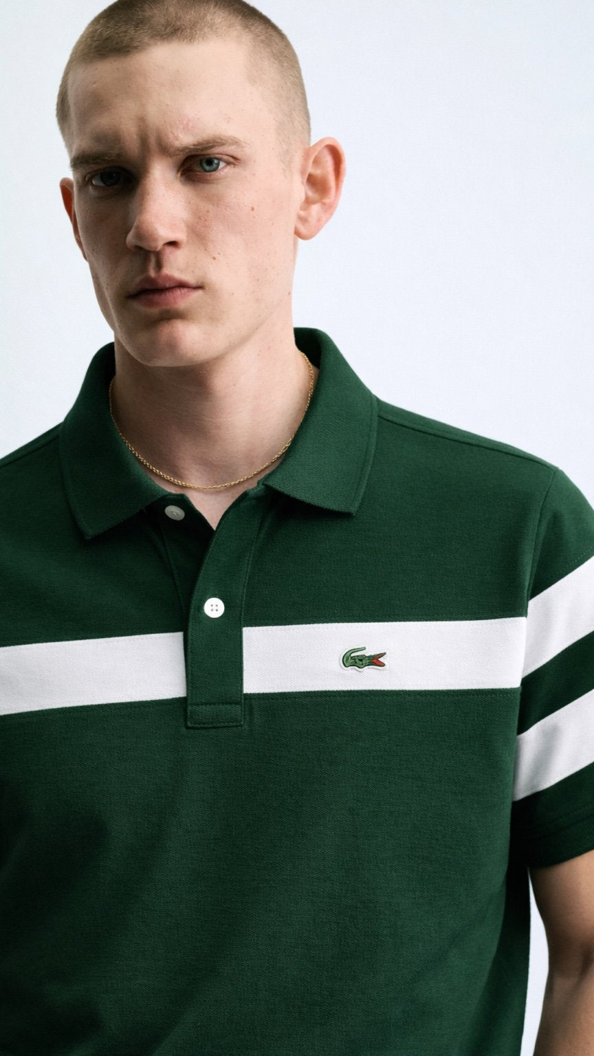 Man wearing a green Lacoste polo shirt with a white stripe on a light gray background