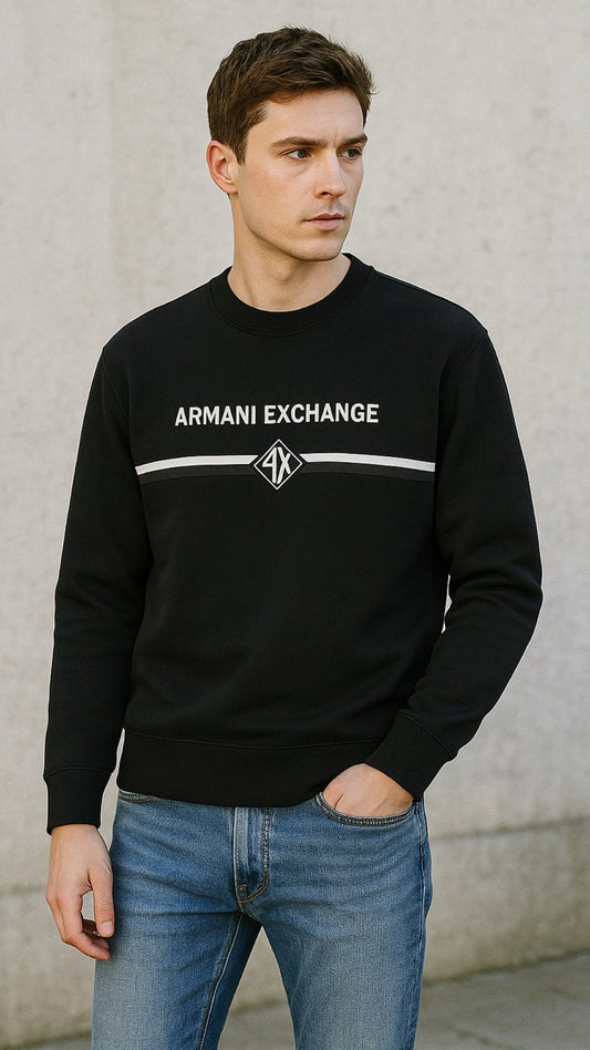 Man wearing a black Armani Exchange sweatshirt against a gray wall.