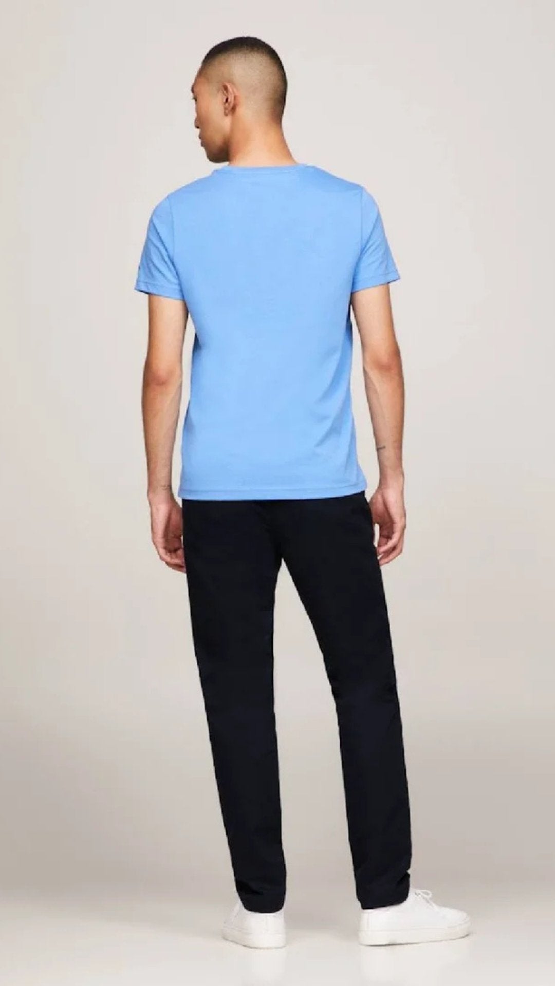 Person wearing a blue t-shirt and black pants on a plain background