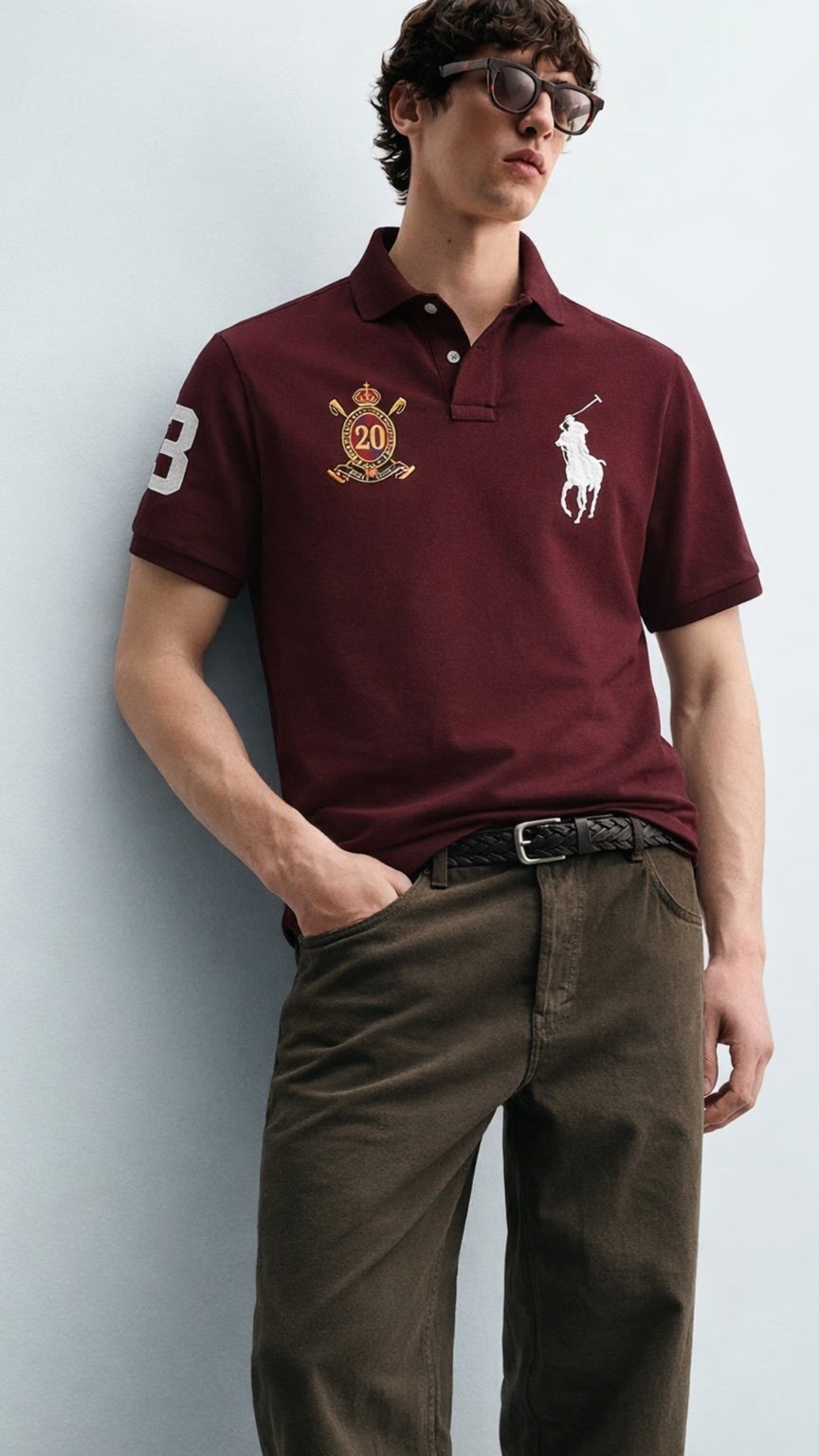Man wearing a burgundy Polo Ralph Lauren shirt with a logo against a light gray background